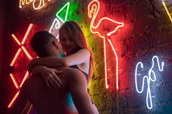 Passionate couple kissing on the background of neon lamps.