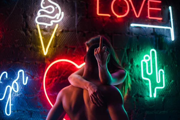 Leidenschaftliches Paar küsst sich auf dem Hintergrund von Neonlampen. — Stockfoto