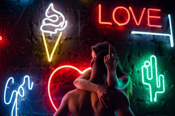 Страстная пара целуется на фоне неоновых ламп . — стоковое фото