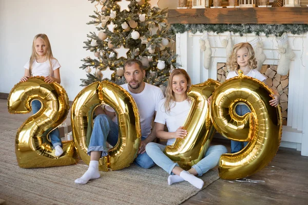 Glückliche Familie hält Schild 2019 aus goldenen Luftballons für das neue Jahr. — Stockfoto