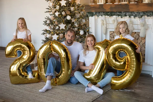 Glückliche Familie hält Schild 2019 aus goldenen Luftballons für das neue Jahr. — Stockfoto