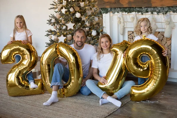 Glückliche Familie hält Schild 2019 aus goldenen Luftballons für das neue Jahr. — Stockfoto