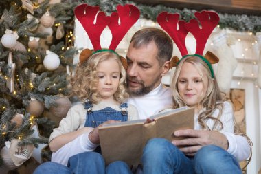 Baba kız Noel ağacı yakınındaki bir kitap okur..