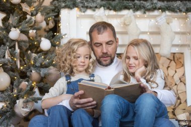 Baba kız Noel ağacı yakınındaki bir kitap okur..