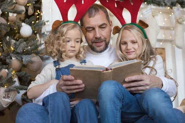 Baba kız Noel ağacı yakınındaki bir kitap okur..