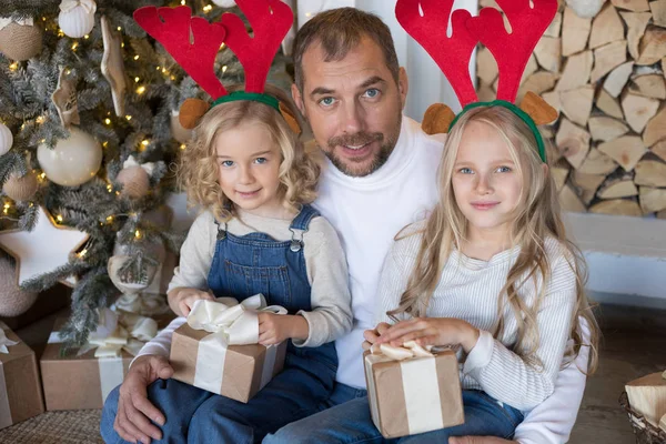 Papa est assis avec deux filles près du sapin de Noël . — Photo