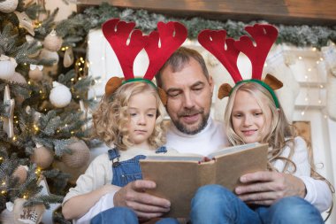 Baba kız Noel ağacı yakınındaki bir kitap okur..