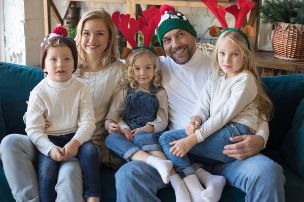 Joyeux famille dans des chapeaux de Noël drôles assis sur le canapé . — Photo