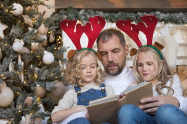 Baba kız Noel ağacı yakınındaki bir kitap okur..