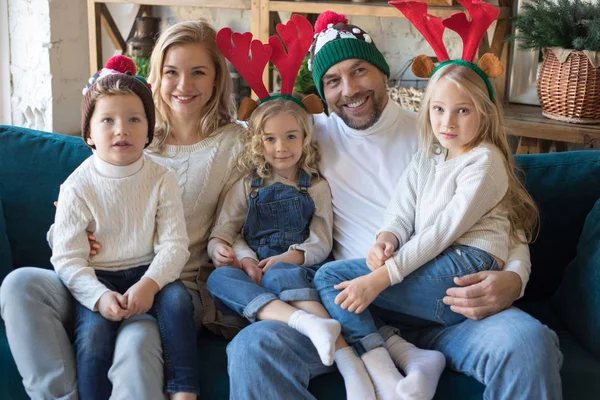 Joyeux famille dans des chapeaux de Noël drôles assis sur le canapé . — Photo