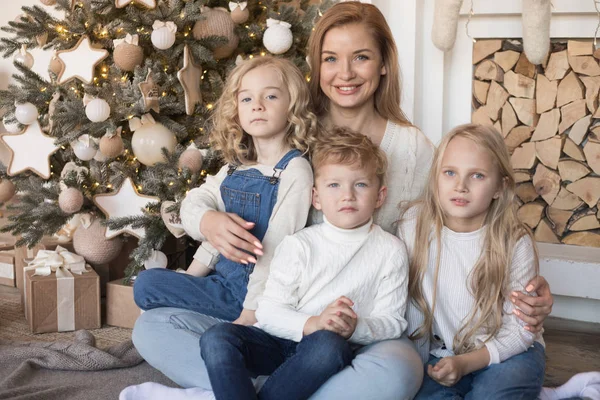 Maman avec des enfants assis près de l'arbre de Noël . — Photo