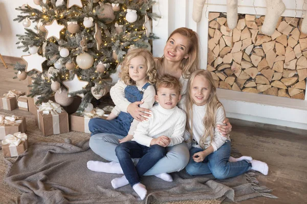 Mutter mit Kindern sitzt am Weihnachtsbaum. — Stockfoto