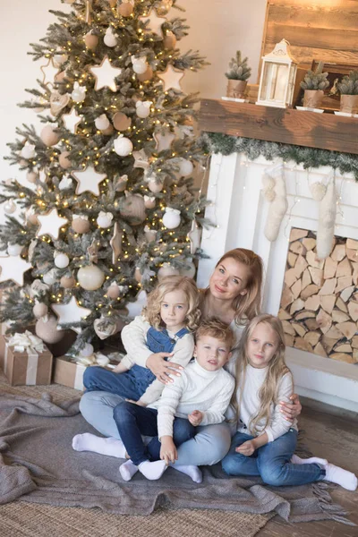 Μαμά με τα παιδιά που κάθονται κοντά το χριστουγεννιάτικο δέντρο. — Φωτογραφία Αρχείου