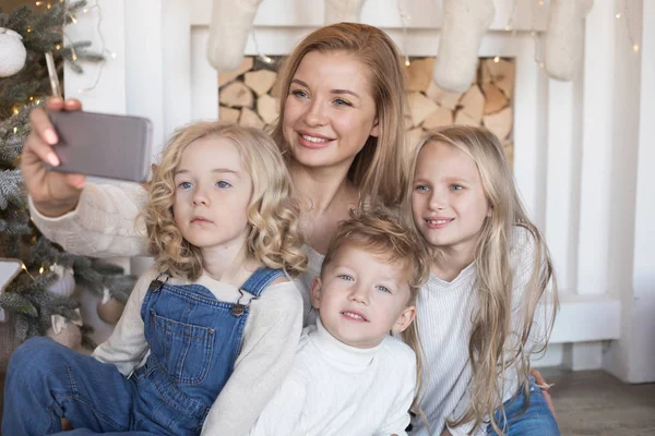 Mutter mit Kindern macht Selfie auf dem Hintergrund des Weihnachtsbaums. — Stockfoto