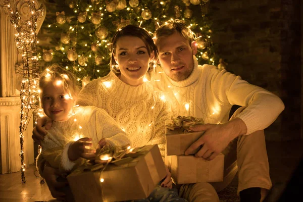 Joyeux famille enveloppé dans une guirlande se trouve près d'un arbre de Noël . — Photo