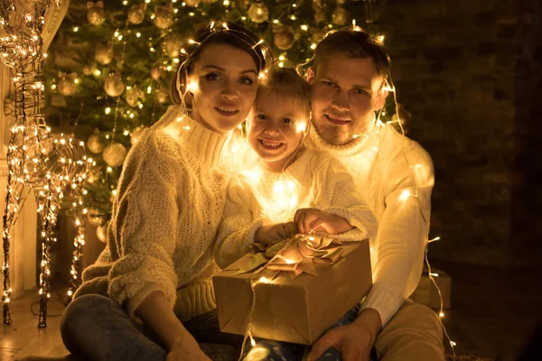 Joyeux famille enveloppé dans une guirlande se trouve près d'un arbre de Noël . — Photo