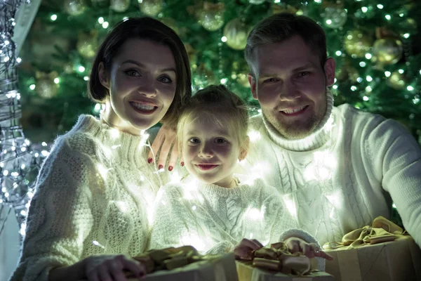 Joyeux famille enveloppé dans une guirlande se trouve près d'un arbre de Noël. Nouvel an . — Photo
