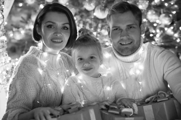 Lycklig familj insvept i en krans sitter nära en julgran. Nytt år. — Stockfoto