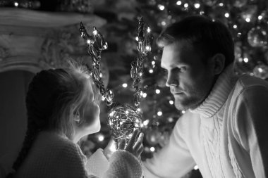 Baba ve kızı ile dekoratif geyik Noel ağacının yanında oturmak.