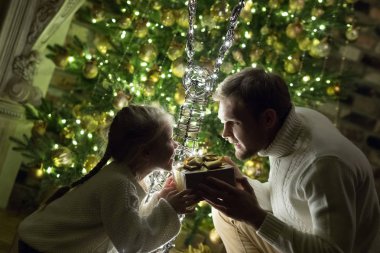 Babası kızı Noel ağacı yakınındaki bir hediye verir..