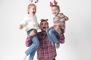 Baba çocuk beyaz bir arka plan üzerinde onun kollarında tutar. Mutlu aile içinde komik Noel saç bantları.
