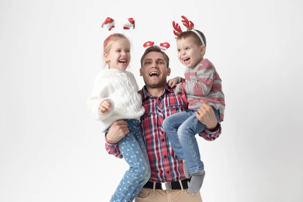 Père tient des enfants dans ses bras sur un fond blanc. Joyeux famille dans les bandeaux de Noël drôles . — Photo