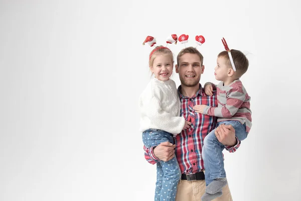 Père tient des enfants dans ses bras sur un fond blanc. Joyeux famille dans les bandeaux de Noël drôles . — Photo