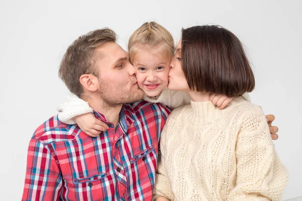 Les parents embrassent leur fille sur la joue sur un fond blanc . — Photo