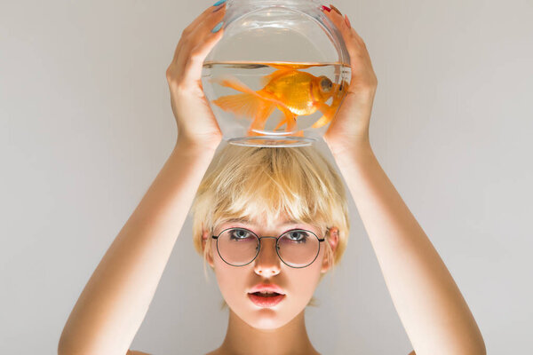 Portrait of a beautiful girl with a goldfish in an aquarium.