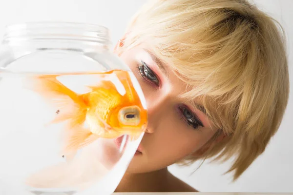 Retrato de una hermosa chica con un pez dorado en un acuario . — Foto de Stock