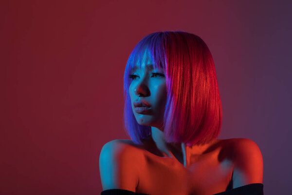 Женщина в красочных ярких огнях позирует в студии
.