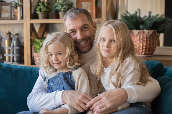 Portret van een vader en twee dochters, zittend in een omhelzing. — Stockfoto