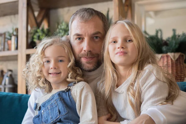 Retrato de un padre y dos hijas sentadas en un abrazo . — Foto de Stock