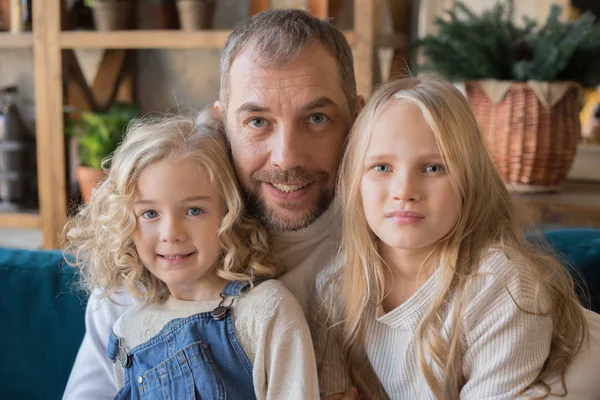 Porträtt av pappa och två döttrar som sitter i en omfamning. — Stockfoto