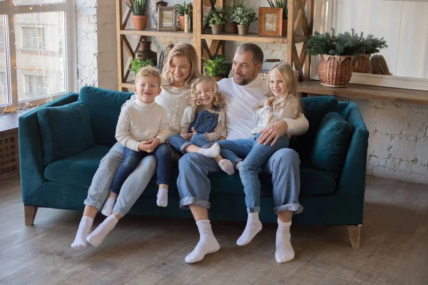 Padres felices y niños divirtiéndose haciendo cosquillas sentados juntos en el sofá . — Foto de Stock