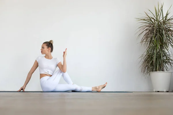 Mujer joven deportiva haciendo práctica de yoga sobre fondo blanco. — Foto de Stock