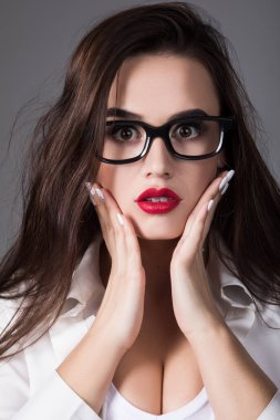 Sürpriz bir ifade ile gözlüklü seksi esmer kadın portresi.