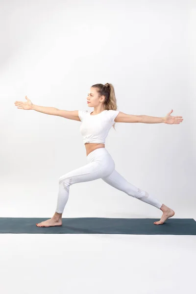 Sportieve jonge vrouw doet yoga praktijk op witte achtergrond. — Stockfoto