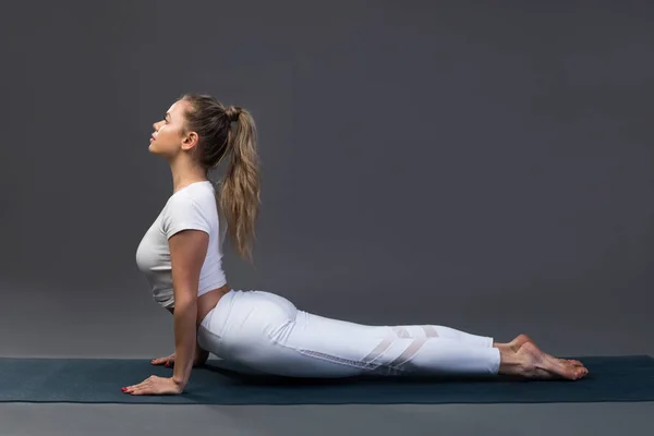 Sportieve jonge vrouw doet yoga praktijk op zwarte achtergrond. — Stockfoto