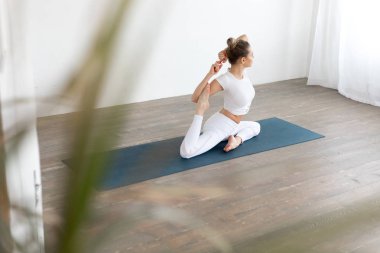 Sportif genç kadının beyaz arka planda evde yoga pratik yapması.