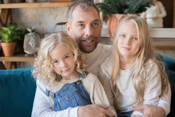 Far sitter med sina två döttrar på soffan hemma. — Stockfoto