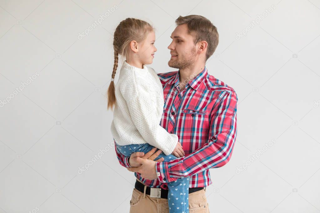 Dad holds daughter in his arms on white background.