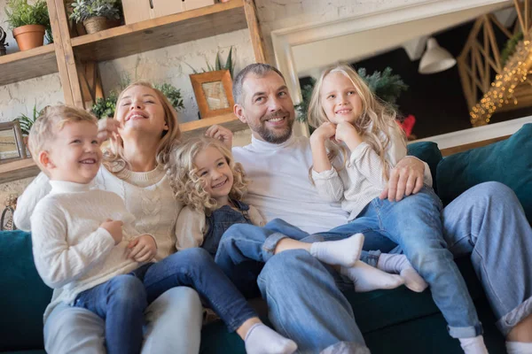 La familia feliz se sienta en el sofá y se divierte . — Foto de Stock