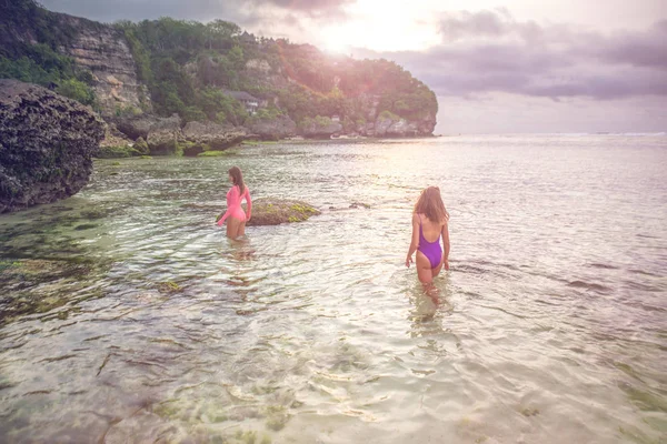 Två vackra kvinnor stå i havet mot en bakgrund av klippor. — Stockfoto