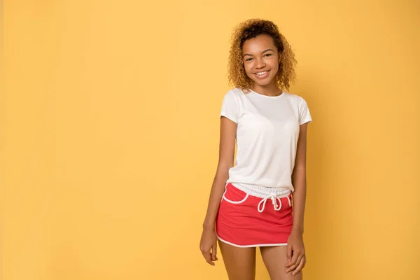 Jonge African American vrouw in een wit T-shirt en een lichte sport rok. — Stockfoto