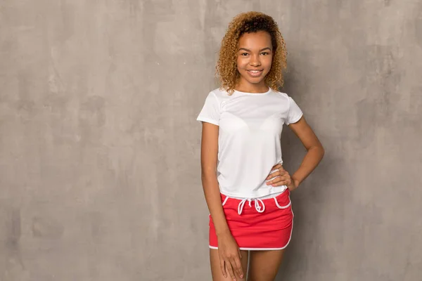 Młody African American kobieta w biały T-shirt i jasne Sport spódnica. — Zdjęcie stockowe