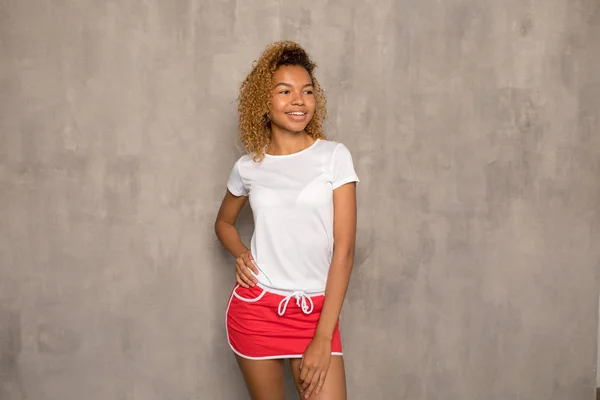 Joven mujer afroamericana con una camiseta blanca y una falda deportiva brillante . — Foto de Stock