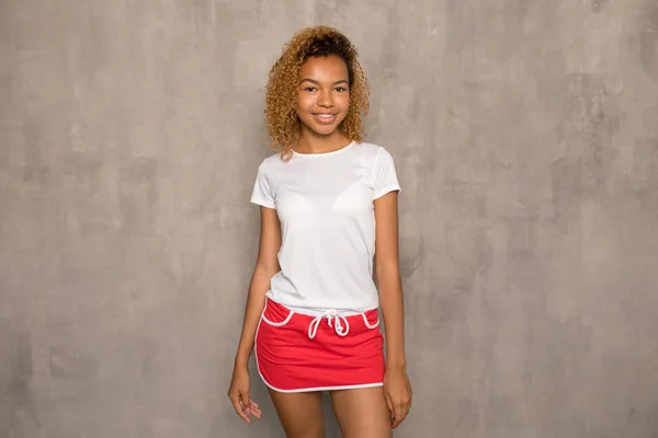 Młody African American kobieta w biały T-shirt i jasne Sport spódnica. — Zdjęcie stockowe