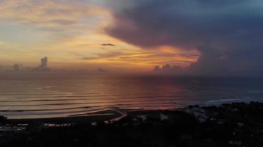 Günbatımı sırasında bulutlu gökyüzüne karşı okyanusun pastoral drone görüntüleri.