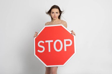 Elinde büyük kırmızı bir dur işareti tutan seksi genç kadın..